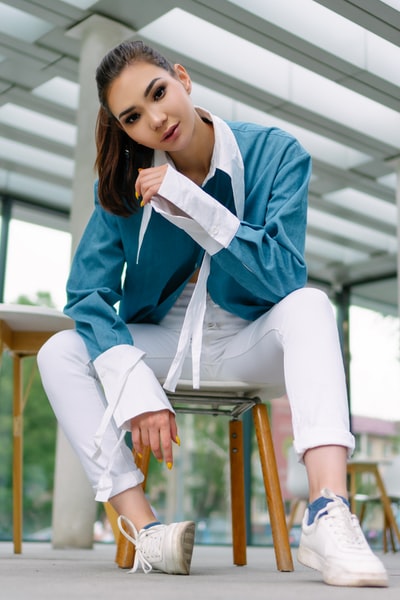 女人在蓝白相间的校服坐在棕色的木头椅子
